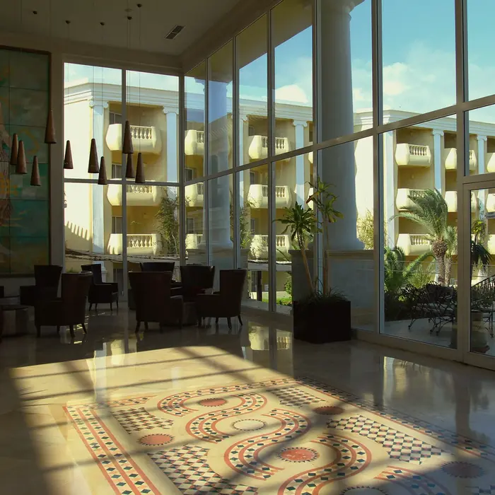 Sunlit hotel lounge with floor-to-ceiling windows and a mosaic floor