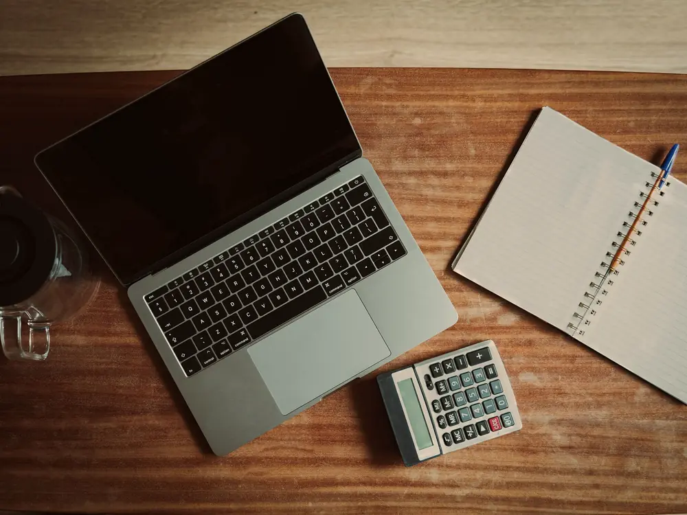 Laptop, calculator and notepad on a wooden desk