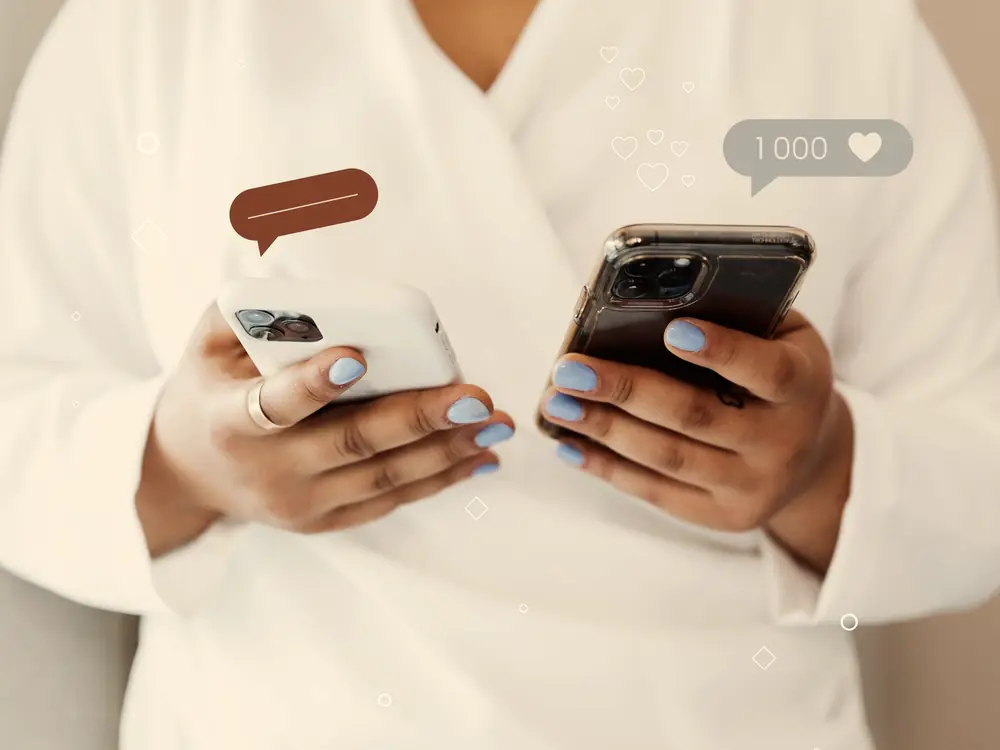 Hands holding two smartphones with social media likes and comment icons