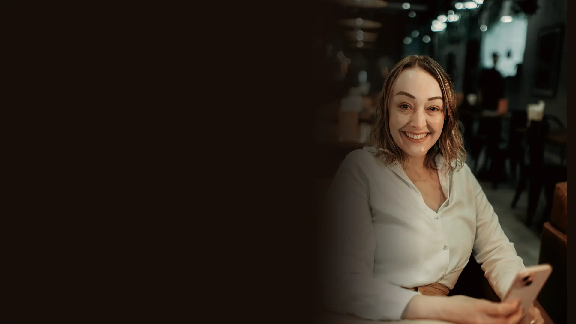 Smiling guest holding a smartphone while seated in a hotel lounge