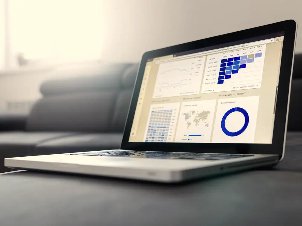 Laptop on a desk displaying pricing charts and a performance dashboard