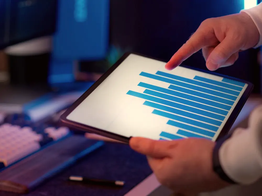 Hand pointing at a bar chart on a tablet showing channel performance data